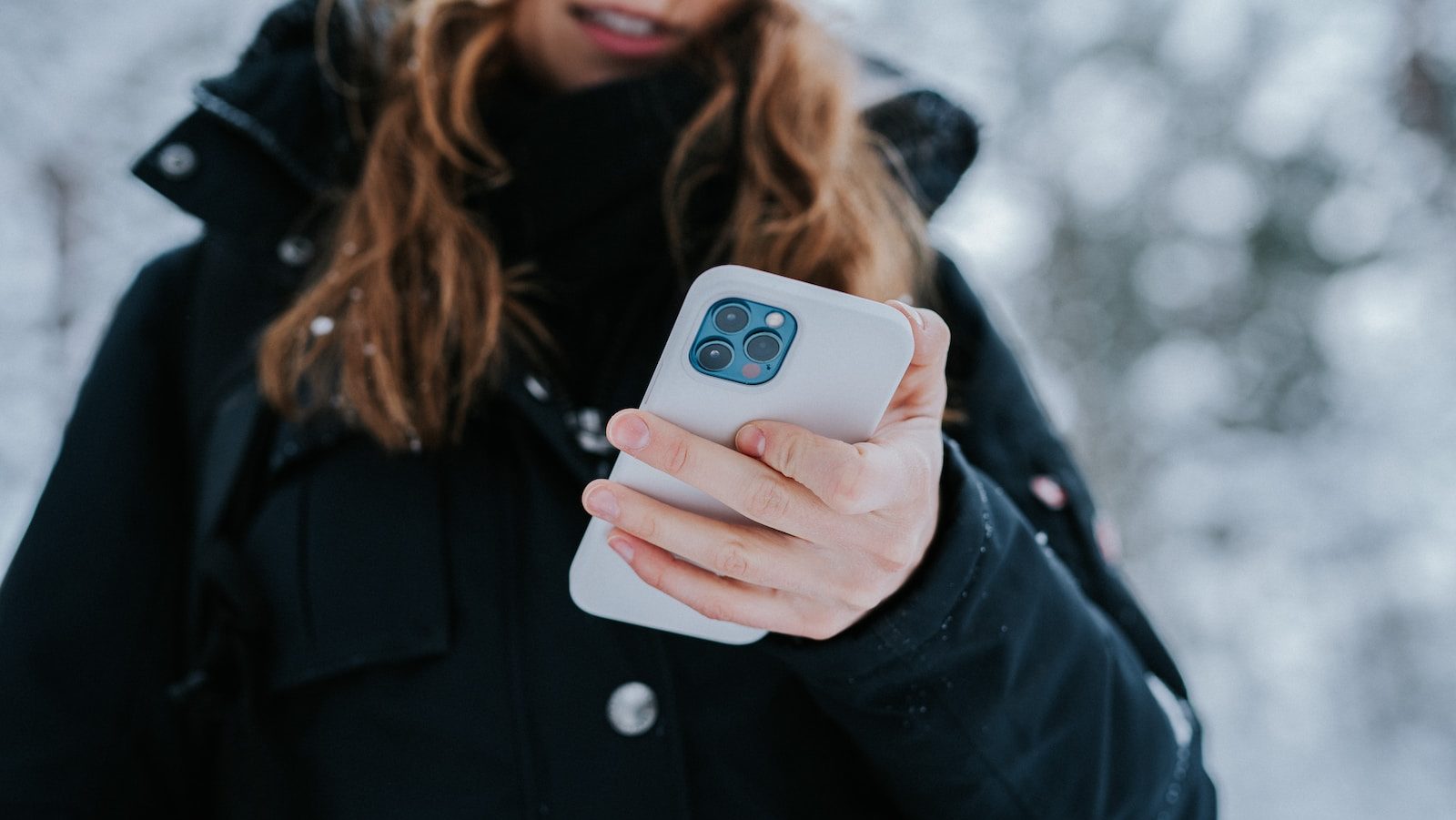 woman in black coat holding white and blue ceramic mug