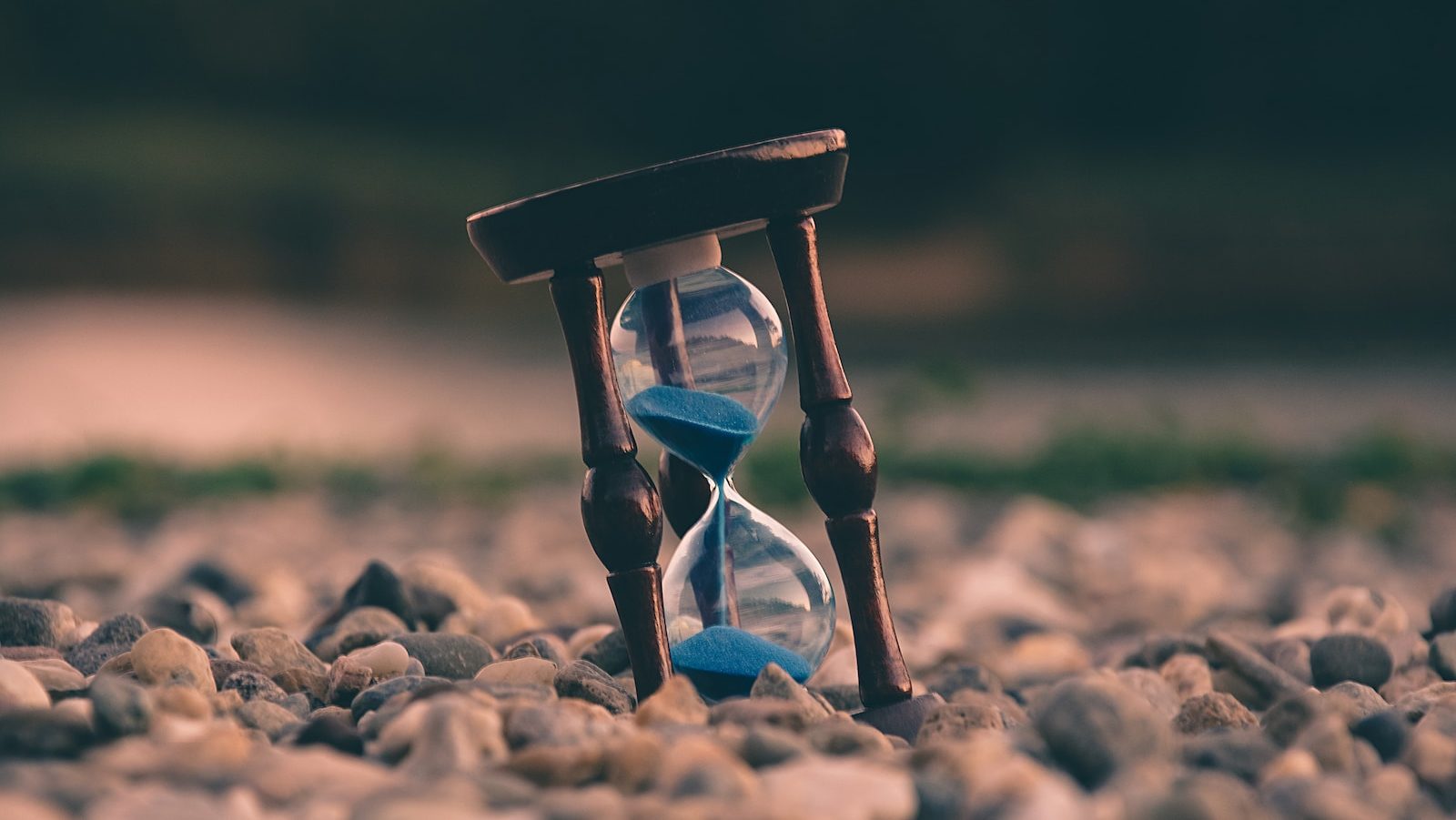 selective focus photo of brown and blue hourglass on stones