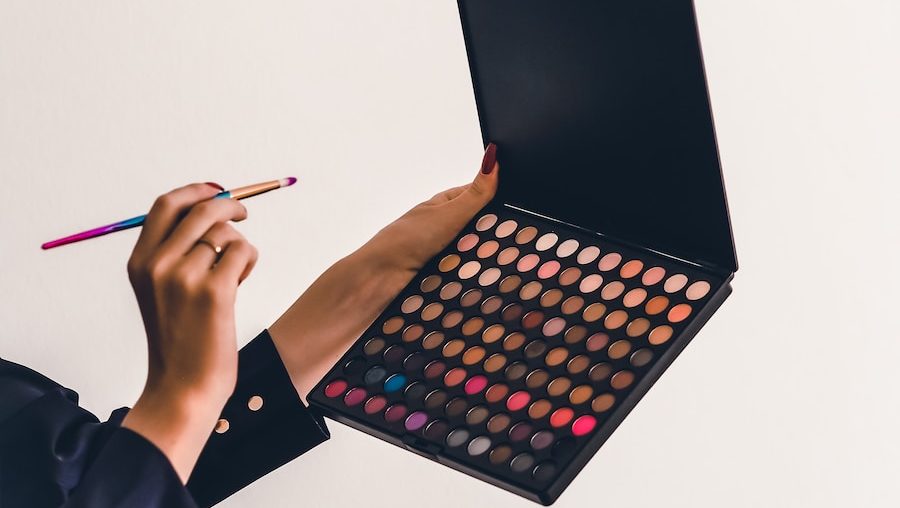 a person holding a makeup palette and a pencil