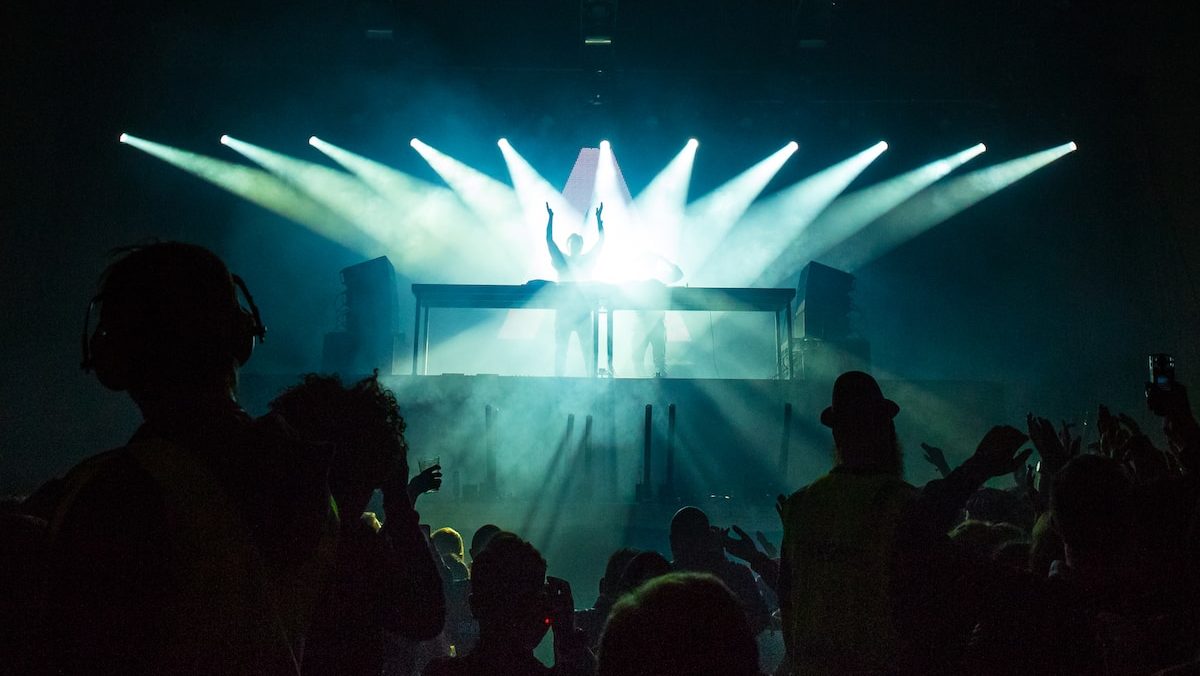 person standing under stage lights facing crowd