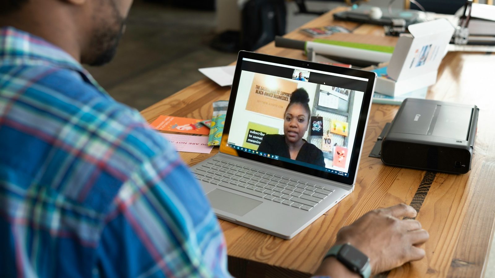 man in blue and white plaid shirt using macbook pro