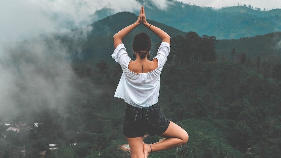 woman standing on rock facing forest