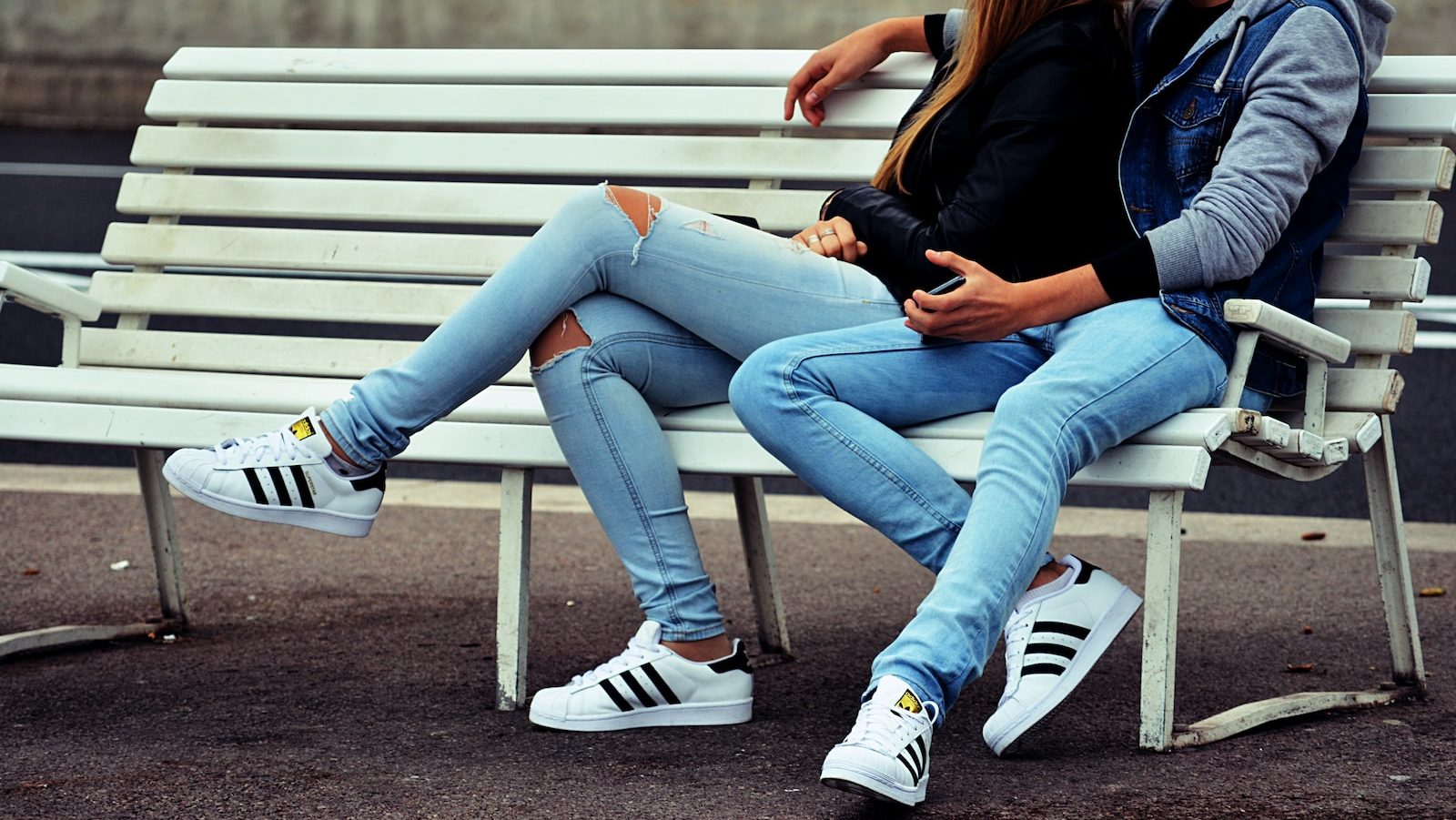 photo of couple sitting on white bench