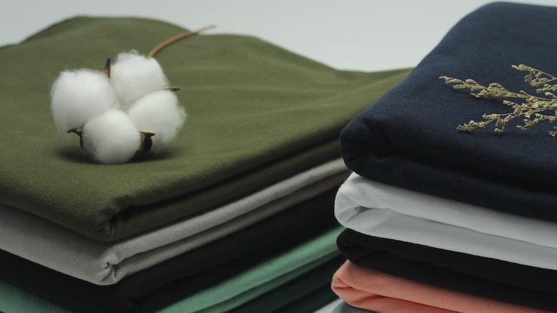 a stack of folded cloths with a cotton ball on top